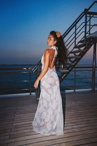 Detail of white semi-transparent halter maxi dress with floral leaf patterns on yacht