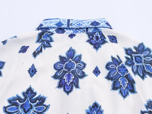 Primer plano del estampado floral azul simétrico en el escote de una camisa blanca de lino