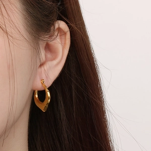 Close-up of a model wearing minimalist golden geometric waterdrop earrings with a polished finish