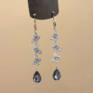 Detail of blue enamel butterfly earrings with hanging teardrop crystal pendant charms