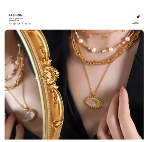 Detail of layered gold necklaces with pearls and colorful beads on a black suit jacket