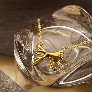 Elegant 18K gold plated stainless steel bow necklace on aesthetic crystal glass background
