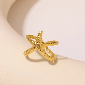 Golden starfish ring with hammered metal texture on a minimalist geometric background