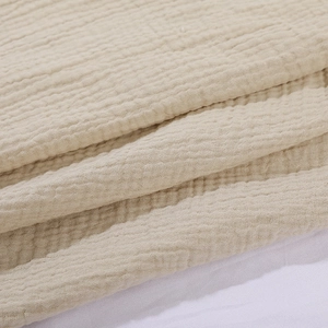 Close-up of soft beige double-layer cotton muslin gauze fabric texture and wrinkles