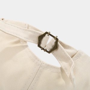 Detailed close-up of the vintage bronze metal adjustment buckle on a beige canvas docker hat