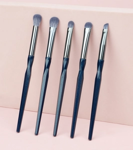 Close-up of five-piece diamond handle eye makeup brushes on a pink geometric stand