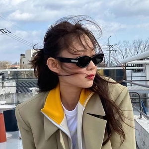 Outdoor model wearing vintage narrow cat eye sunglasses in black with casual blazer