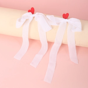 Detail of red heart resin stud earrings with elegant long white sheer ribbon tassels