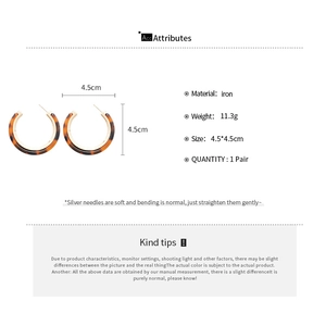 Detail view of C-shaped resin earrings with leopard pattern and silver needle specs