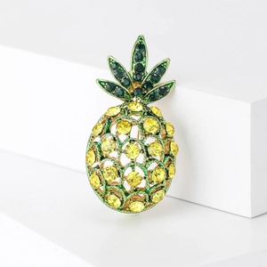 Detail shot of pineapple brooch with yellow and green crystals on golden base
