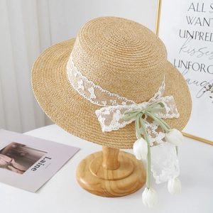 Detail of straw hat with white lace trim, green ribbon bow and tulip flower charms
