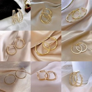 Collection of elegant gold hoop and geometric earrings on soft satin background