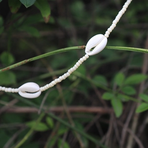 Dettaglio della collana bohémien con perline bianche e ciondoli in conchiglia naturale