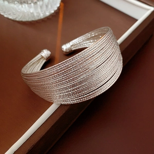 Detail showing the multi-layer woven texture and silver finish of the open cuff bracelet