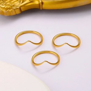 Three minimalist gold V-shaped heart rings arranged in a triangle on light gray background