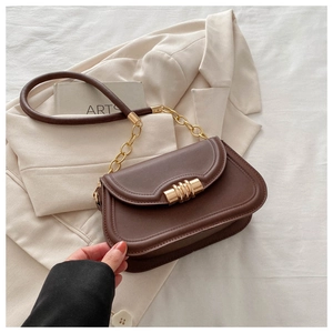 Detail showing brown saddle bag with gold cylinder lock and leather chain strap