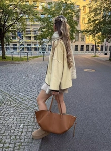 Detail view of light yellow coat with high neck and embroidery in a street style setting