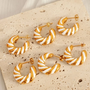 Golden hollow geometric earrings with white enamel twisted ring design on beige stone