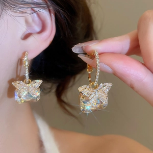 Macro shot of butterfly earrings with gold plating and faceted square zircon stones