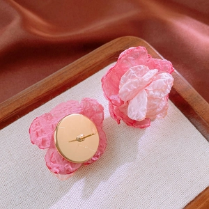 Macro view of handmade pink lace flower clip-on earrings with gold metal backing details