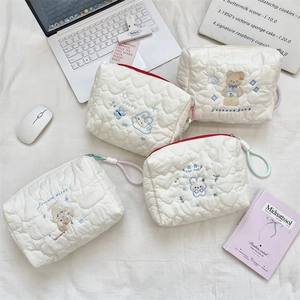 Close-up of heart-quilted toiletry bags with embroidered cartoon bears and rabbits