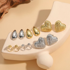Detail view of gold and silver heart-shaped and geometric earrings on a display stand