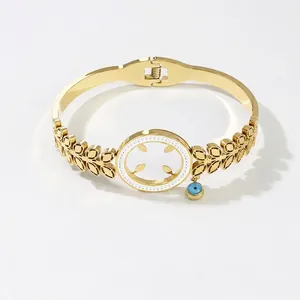 Gold hollow leaf pattern bangle with blue Evil Eye charm on a clean white background