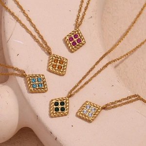 Detail of 18K gold plated square pendants with four colorful zircons on stone background