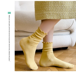 Detail of yellow ribbed crew socks with ruffled cuffs worn in a cozy home setting