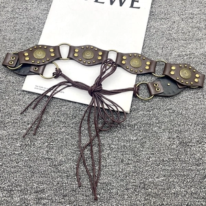Macro detail of Y2K vintage leather belt with bronze studs and metal ring connectors