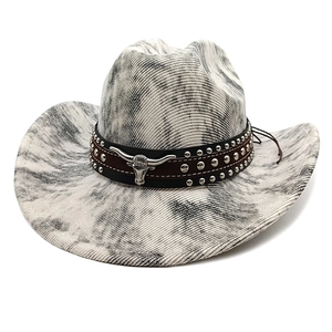 Detail eines Cowboyhuts mit Marmortextur und silbernem Stierkopf-Emblem am Hutband
