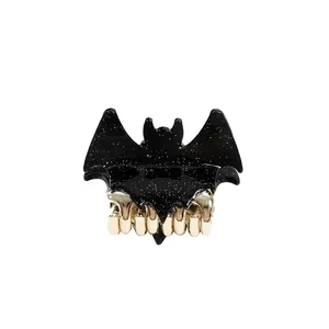 Sparkling bat-shaped hair claw clip with black glitter finish and gold metal teeth