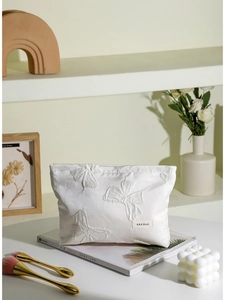 Beauty case bianco in tessuto con texture a fiocco 3D ed etichetta del marchio