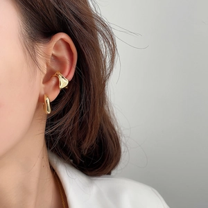 Close-up of a model wearing gold irregular fluid shape silver ear cuffs with metallic texture