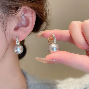 Close-up of model holding elegant grey pearl earrings with sparkling zircon accents