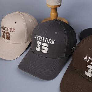 Détail de la broderie ATTITUDE 35 sur casquettes en toile de coton de diverses couleurs