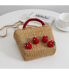 Détail du sac en paille tissé avec fraises au crochet et poignée en velours rouge