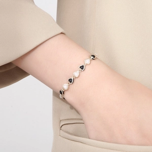 Minimalist heart pearl link bracelet in stainless steel worn on a model wrist