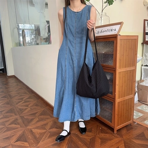 Détail d'une robe longue sans manches en denim bleu avec coupe évasée et surpiqûres
