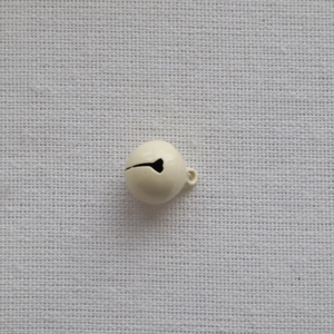 Close-up of a 14mm cream-colored metal bell with a smooth painted finish on beige fabric