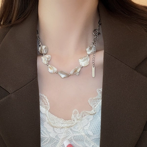 Dettaglio di perle barocche con catena argentata indossate da una modella in abito