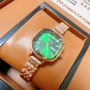 Macro view of women's quartz watch with green sunray dial and gold metal link bracelet