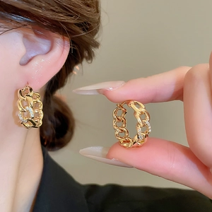 Macro shot of gold plated Cuban link earrings with sparkling inlaid zircon stones