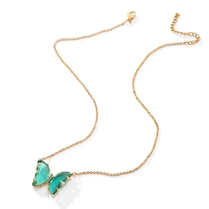 Detailed view of butterfly pendant with green crystal wings on gold stainless steel chain