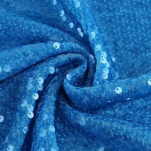 Detailed close-up of blue sequins and mesh fabric with elegant spiral folds