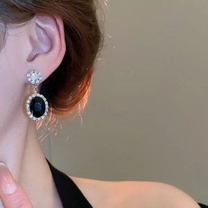 Detail shot of vintage silver pendant earring with oval black gemstone and white zircon