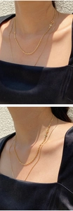 Double-layered gold cross necklace with a minimalist aesthetic worn by a model in sunlight