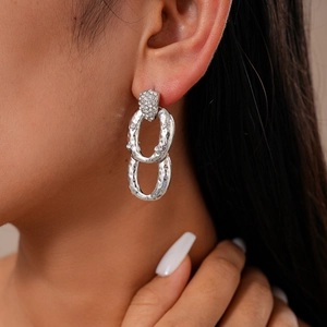 Primo piano di orecchini ovali in argento con zirconi luccicanti su modella femminile