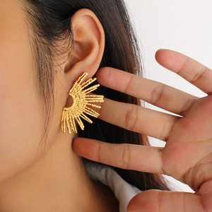 Close-up of 18K gold plated stainless steel fan earrings with textured sunburst design