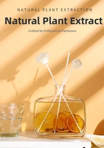 Detailed view of glass reed diffuser with orange slices and decorative white flowers